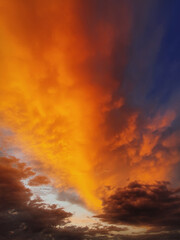 Naklejka premium Colorful autumn sunset sky. Vertical background, abstract clouds shapes and colors. October seasonal celestial beauty. Panoramic dusk cloudscape scene. Misty overcast cumulus, abstract nebula textures