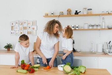 Young mother and her two kids making vegetable salad