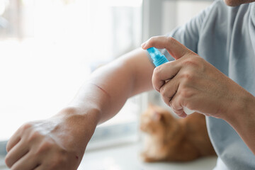 A man is spraying alcohol on a cat scratch wound Cleaning and disinfection : First aid concept in...