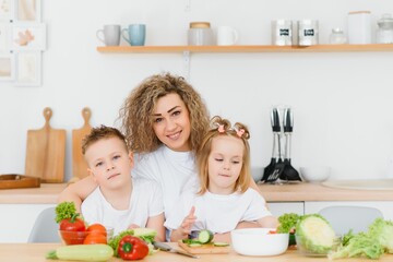 mother with children preparing vegetable salad at home