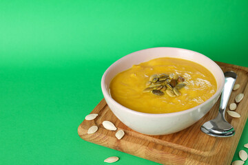 Concept of tasty food with pumpkin soup on green background