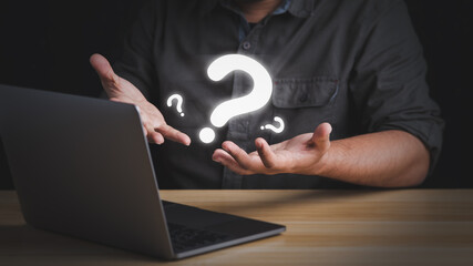 A businessman has many questions wondering what to do next in front of his laptop.