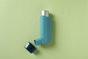 Blue asthma inhaler on green background, top view