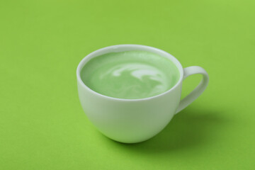 Cup of matcha latte on green background