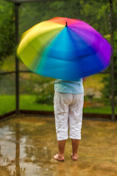Women twirling colorful umbrella in the rain on a lanai in Wesley Chapel, Florida.