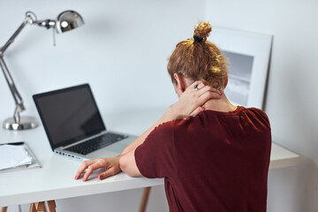 Woman working from home on a laptop and having pain in the neck.