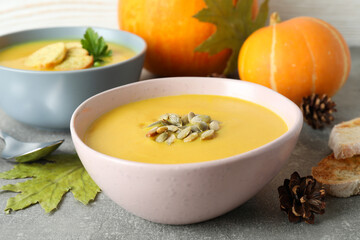 Concept of tasty food with pumpkin soup on gray textured table