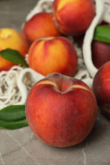 Fototapeta na wymiar String bag with peach fruits on gray textured table