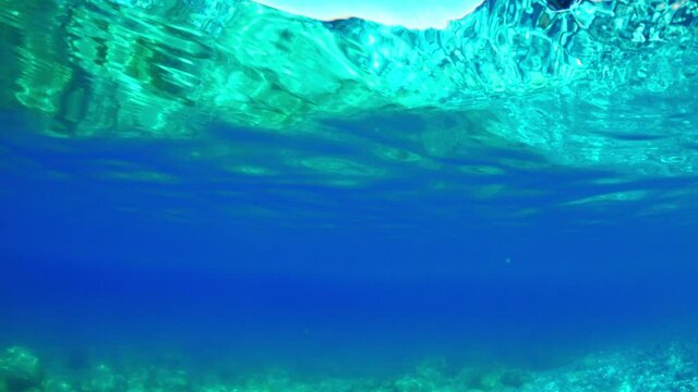 Slow-motion half underwater video at the border of air and water. Beautiful rocky beach on the Adriatic Sea in Montenegro.
