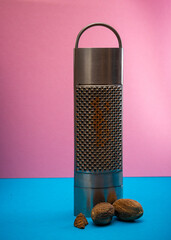 nutmeg grater on a pink and blue background cooking concept , spices . - obrazy, fototapety, plakaty