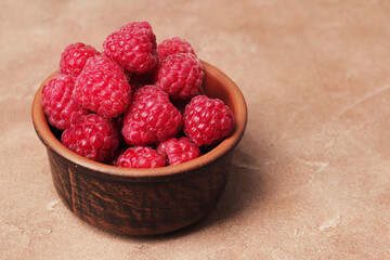composition of ripe raspberries in a bowl on a textured background