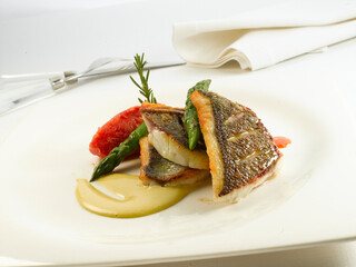 Lubina con verduras frescas sobre fondo blanco. Sea bass with fresh vegetables on white background