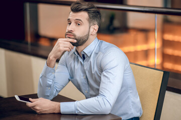 Young bearded man sitting at the table and waiting