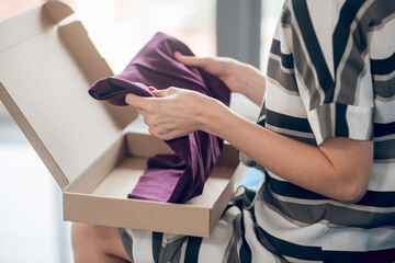 Experienced saleswoman preparing a garment for shipping