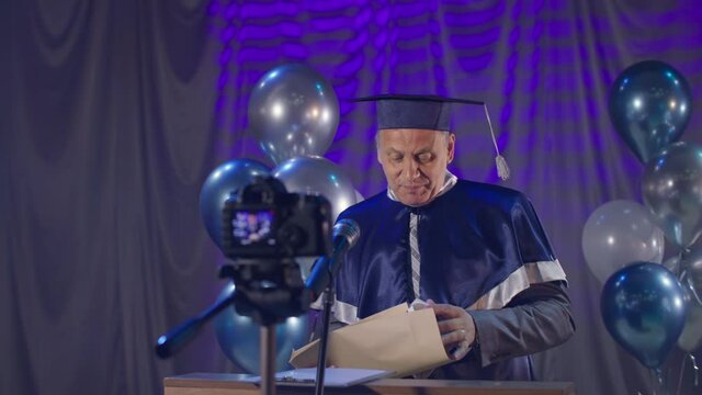 male rector in mantle solemnly conducts graduation ceremony for university graduates using modern video communication technologies during quarantine due to coronavirus