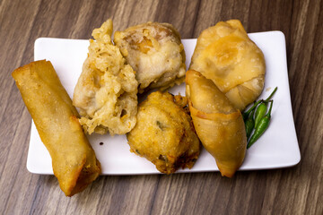 Gorengan is a typical snack from Indonesia. Usually consists of tempeh, tofu, cassava, martabak, and bananas. This food is usually sold by street vendors at cheap prices. Photographed on white plate 