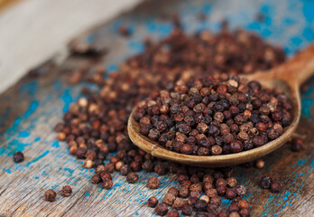 An image of close-up black pepper spice peppercorn on a wooden spoon is an ingredient or food spicery flavor white background.