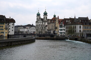 Lucerne, Switzerland 04 17 2021: Waterfront of Lucerne, old city along the river Reuss, with dominant Jesuit church and Reuss Bridge in the foreground. 