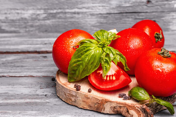 Ripe tomatoes with fresh basil leaves, black salt, and peppercorn
