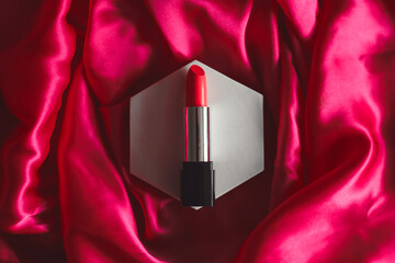 Red lipstick on a textured silk background, beauty cosmetics.