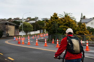Fototapeta premium Man riding bicycle on the street with traffic cones in the middle of the road