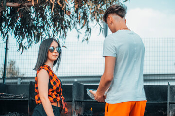 Pareja de muchachos jóvenes cocinando una barbacoa al aire libre junto a los arboles 