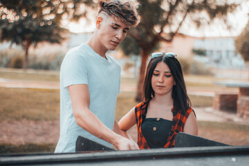 Chico y chica joven haciendo una barbacoa en un parque junto a la puesta de sol