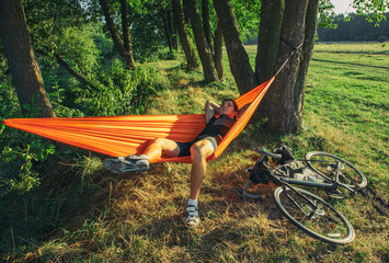Bike traveler resting in the hammock after long day riding bicycle packed by bags