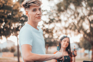 Hombre joven adolescente en una barbacoa con cerveza sonriendo con amigos 