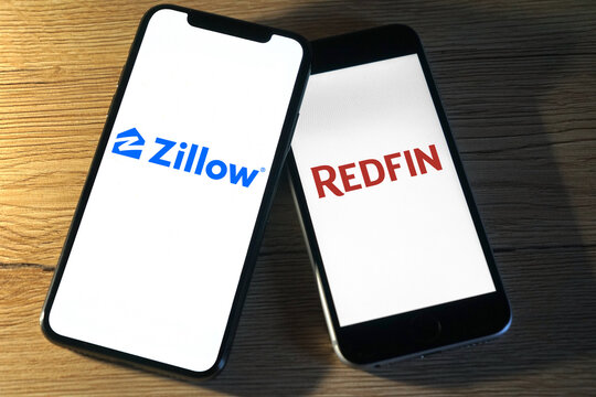 Zillow and Redfin logos are displayed on two smartphones next to each other, online real estate marketplace, house purchase, financing, 2021