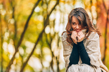 Pretty woman with luxurious hair resting on the autumn forest. Background of an autumn park. Close-up