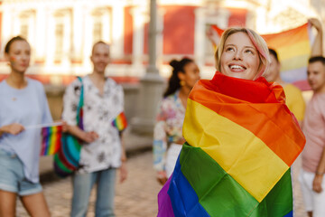 White woman with rainbow flag smiling during pride parade