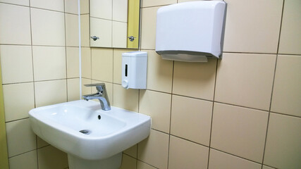 Modern bathroom white sink and faucet in public toilet and restroom. Tap, soup, paper. Virus protection concept. Sanitary rules and requirements. Contemporary washroom and wc in office centre. Hygiene
