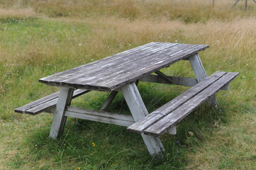 Wooden table and benches for outdoor dining and picnic on a grass field at the camping