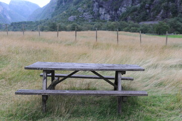 Wooden table and benches for outdoor dining and picnic on a grass field at the camping