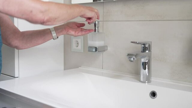Woman hand washing with liquid soap over bathroom sink, close-up of female hands using antibacterial sanitizer, coronavirus COVID-19 prevention, hygiene