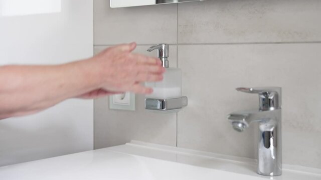 Woman hand washing with liquid soap over bathroom sink, close-up of female hands using antibacterial sanitizer, coronavirus COVID-19 prevention, hygiene
