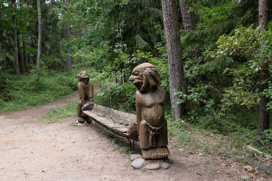 Schwerstarbeit beim Tragen einer schweren Bank  - eine interessante Holzskulptur im Wald bei Juodkrante auf der Kurischen Nehrung in Litauen