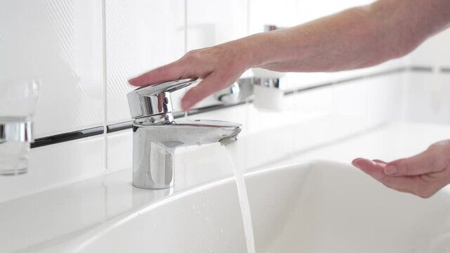 Hand washing with liquid soap, close-up of female hands rinsing with water over bathroom sink, woman using antibacterial sanitizer, coronavirus COVID-19 prevention, hygiene