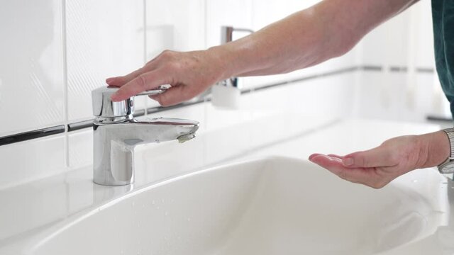 Hand washing with liquid soap, close-up of female hands rinsing with water over bathroom sink, woman using antibacterial sanitizer, coronavirus COVID-19 prevention, hygiene
