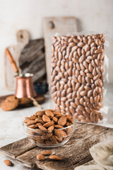 Dried almonds in a glass bowl and in a vacuum-packed coffee pot on a light background.