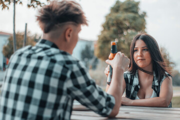 Naklejka premium Cita romantica de dos jovenes en un picnic al aire libre brindando con sus cervezas de cristal