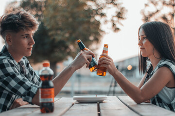 Cita romantica de dos chavales en un picnic al aire libre brindando con sus cervezas de alcohol
