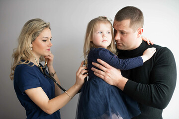 Father with girl being examined by female pediatrician in clinic