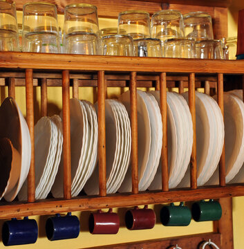 Estante escurridor de madera para platos, tazas y vasos en la cocina de una casa tradicional en un pueblo espa&ntilde;ol. Espetera de cocina