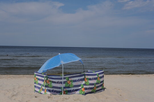 Colorful screen with umbrella or parasol on a sand beach on a sunny day at the seashore