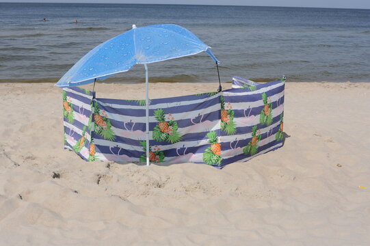 Colorful screen with umbrella or parasol on a sand beach on a sunny day at the seashore