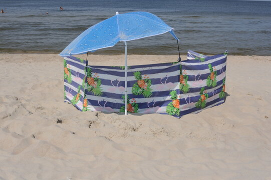 Colorful screen with umbrella or parasol on a sand beach on a sunny day at the seashore