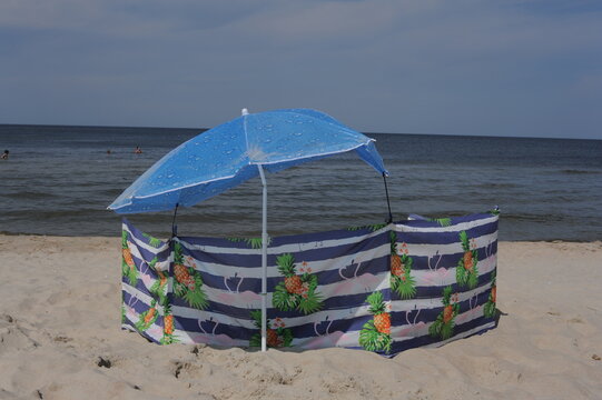 Colorful screen with umbrella or parasol on a sand beach on a sunny day at the seashore