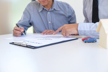 Sales manager giving advice application form document, considering mortgage loan offer for car and house insurance.